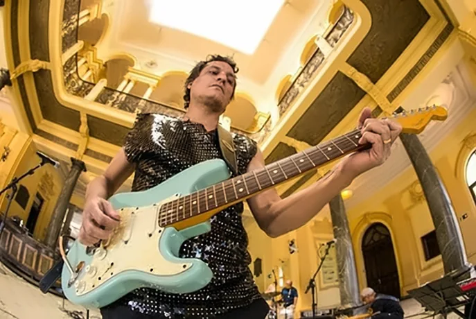 Aldrin Gandra tocando guitarra em um salão histórico durante o Festival Mao Sessions